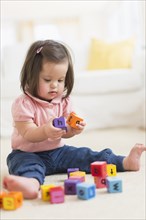 Hispanic toddler with Down syndrome playing with blocks