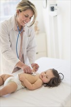 Hispanic doctor listening to toddler's heartbeat