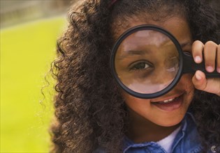 Mixed race girl using magnifying glass