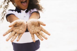 Mixed race girl with sandy hands on beach