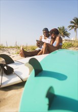 Couple using digital tablet on beach