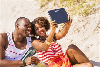 Couple taking pictures with digital tablet on beach