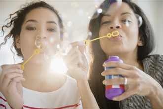 Mother and daughter blowing bubbles together