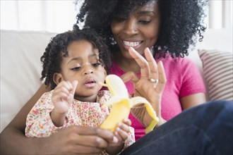 Mother and daughter eating banana