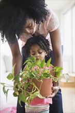 Mother and daughter carrying plant together