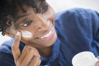 Black woman applying lotion to her cheek