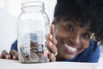 Black woman saving coins in jar