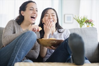 Women laughing on sofa together