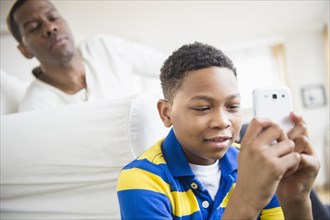 Father watching son use cell phone