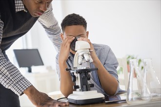 Teacher helping student use microscope in science class