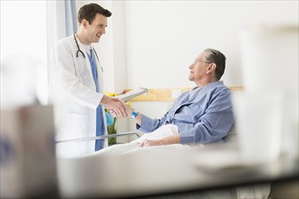 Caucasian doctor shaking hands with Senior patient in hospital