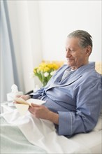 Senior Caucasian man reading in hospital bed