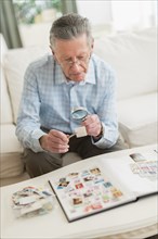 Senior Caucasian man examining stamp collection