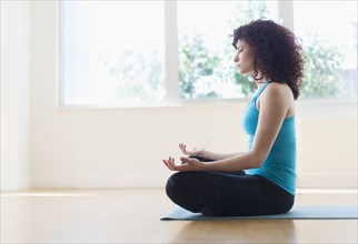 Hispanic woman meditating on yoga mat