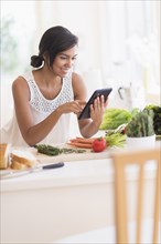 Hispanic woman cooking with digital tablet