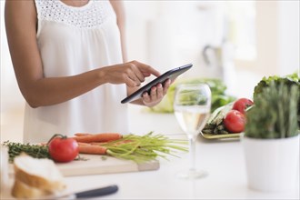 Hispanic woman cooking with digital tablet in kitchen