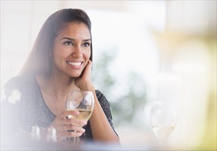Hispanic woman having glass of wine in restaurant