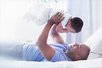 Father playing with baby on bed