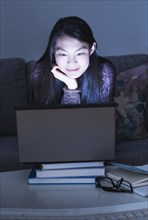 Mixed race teenage girl using laptop on sofa