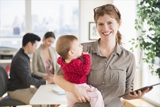 Businesswoman holding baby in office
