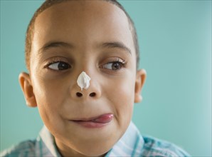 Mixed race boy with icing on nose