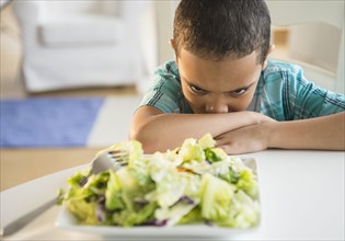 Mixed race boy refusing to eat salad