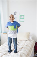 Mixed race boy standing on bed