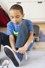 Mixed race boy tying his shoelaces