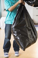 Mixed race boy taking out garbage
