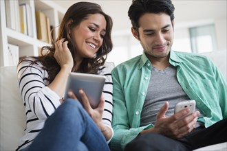 Couple using technology together on sofa