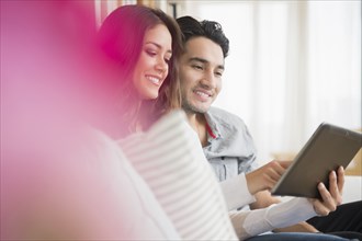 Couple using tablet computer on sofa