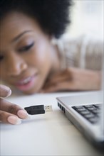 African American woman plugging USB cable into laptop
