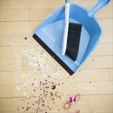 Broom and dustpan with confetti on floor