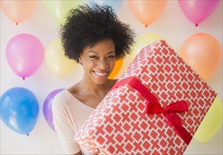 African American woman holding wrapped gift at birthday party