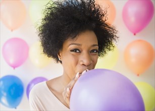African American woman blowing up balloon for party