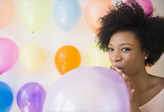 African American woman blowing up balloon for party