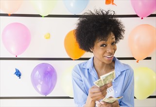 African American woman counting money at balloon wall