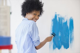 African American woman painting wall