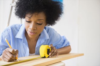 African American woman measuring wood