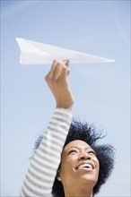 African American woman throwing paper airplane