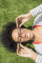 African American woman laying in grass wearing eyeglasses