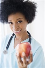 African American nurse holding apple