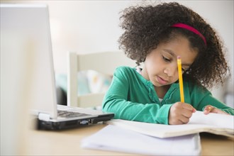 African American girl doing homework with laptop