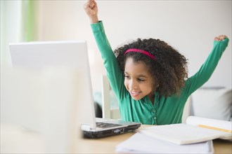 African American girl cheering at laptop