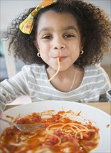 African American girl eating spaghetti at table