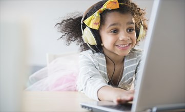 African American girl listening to headphones and using laptop