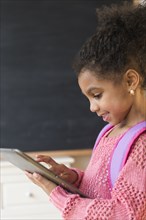 African American girl using tablet computer in classroom