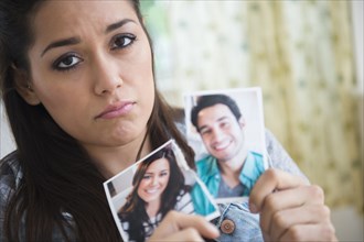 Woman holding torn picture of herself with ex-boyfriend