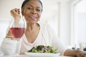 Mixed race woman eating salad at table