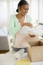 Woman packing bowl in cardboard box